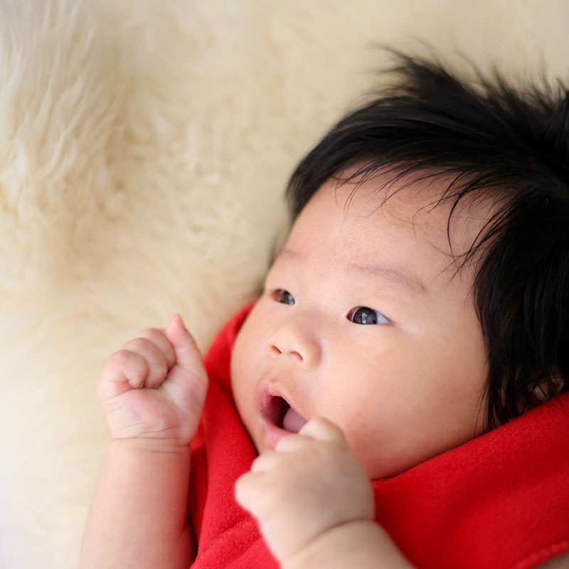 bébé aux cheveux noirs avec un pull rouge